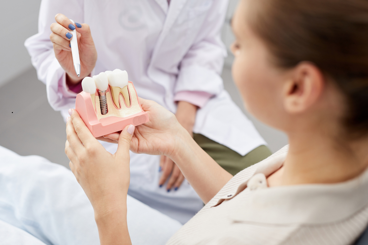 Dentist explaining dental implant model to patient during consultation.