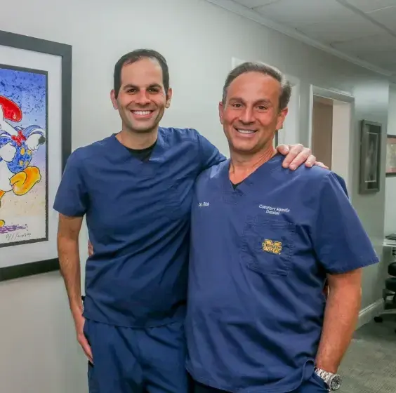 Two dental professionals smiling together in a Center Line dental office.