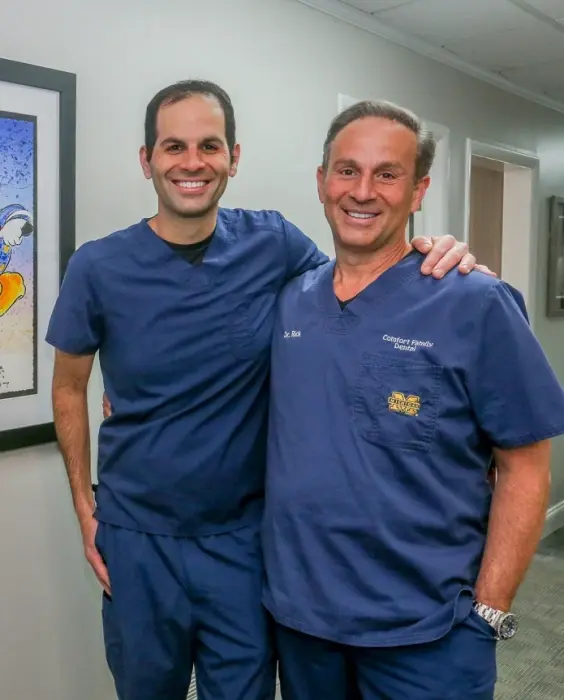 Two dental professionals smiling together in a clinical setting in Center Line, Michigan.